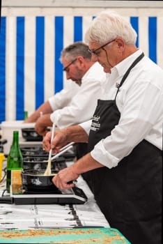 September 28 2019, Charmey, Fribourg, Gruyeres, Switzerland : men are cooking the half-and-half fondue caquelons in Charmey accompanied by Swiss white wine during the transhumance festival