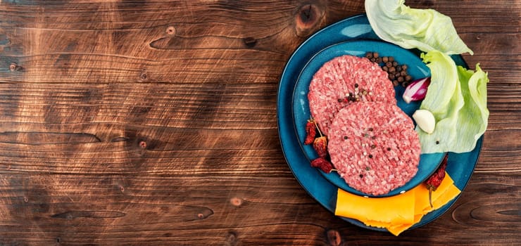 Raw burger cutlets and ingredients on the table. Top view. Copy space.