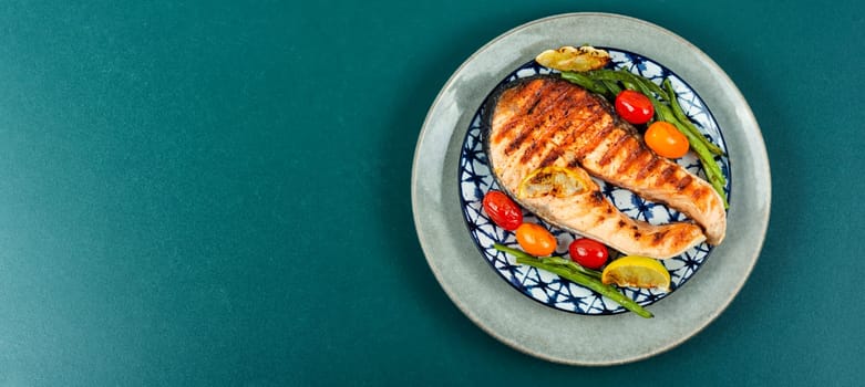 Grilled salmon steak with grilled vegetables, fried fish. Flat lay with copy space.