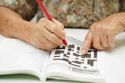 elderly woman playing sudoku puzzle game for treatment dementia prevention and Alzheimer disease.