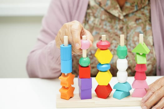 Asian elderly woman playing puzzles game for treatment dementia prevention and Alzheimer disease.