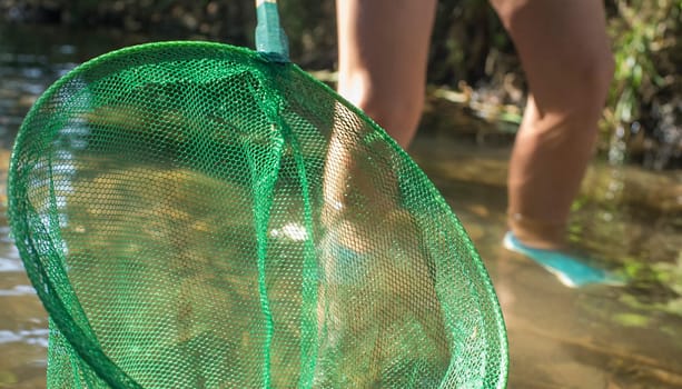Little boy playing with fishing net in the river. Holidays where kids can go wild concept
