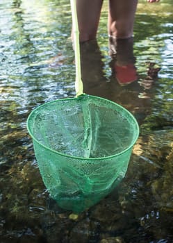 Little girl playing with fishing net in the river. Holidays where kids can go wild concept