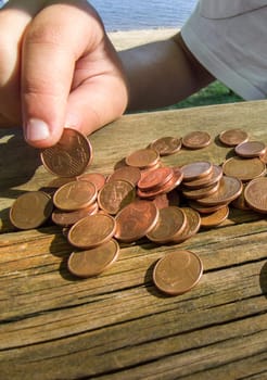 Little girl counting her pocket change savings. Weathered picnic table as background