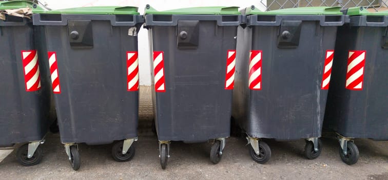 Line of grey dumpsters on sideway. Long format view
