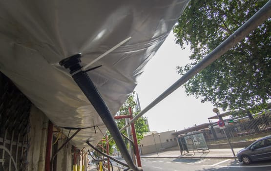 Scaffold equipped with pedestrian protection devices. Dust collection tubes. Ground level