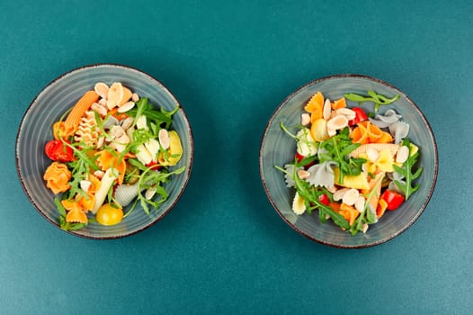 A bowl with traditional pasta salad with fresh tomatoes and herbs.