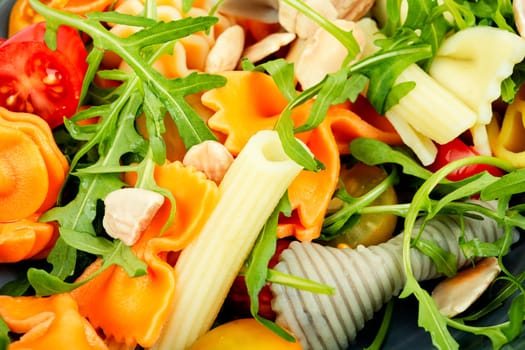 Salad with fresh tomatoes, greens and pasta on a plate. Healthy diet food. Close up.