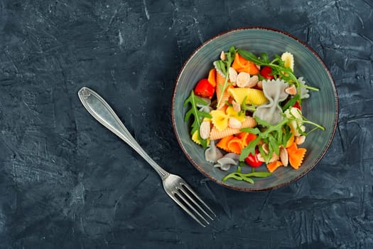 A bowl with traditional pasta salad with fresh tomatoes and herbs. Top view with copy space.