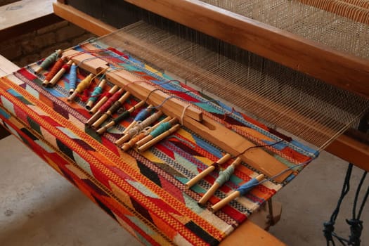 Traditional loom with unfinished colorful carpet on it, colorful threads lying on top of it, Oaxaca, Mexico 2022