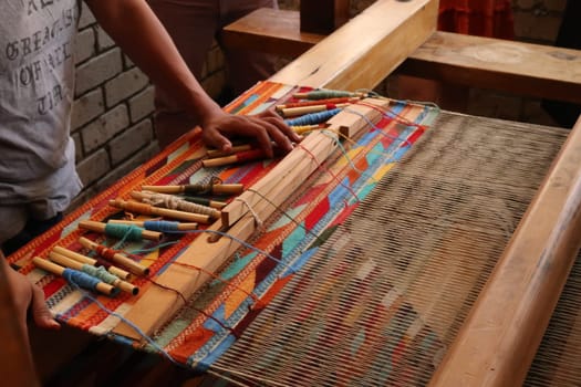 Man in a workshop standing next to a traditional loom, about to weave a colorful carpet, Oaxaca, Mexico 2022
