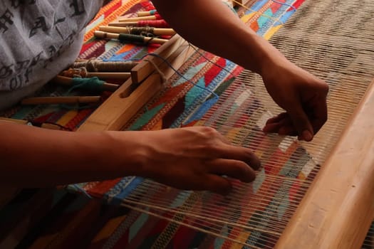 Man in a workshop weaving a colorful carpet on a traditional loom, Oaxaca, Mexico 2022