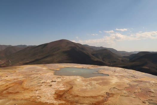 One of natural travertine pools in front of the hilly landscape of Oaxaca at Hierve El Agua, Mexico 2022