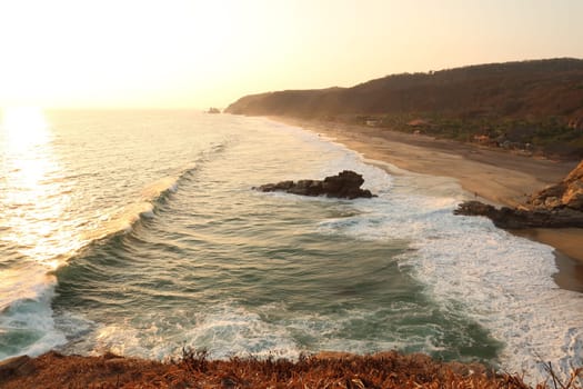 Spectacular view from the view point Punta Cometa onto Playa Mermejita/Mermejita Beach with a big wave building up in the golden sunset, Mazunte, Mexico 2022