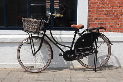 an old black bicycle parked on a wall with a window