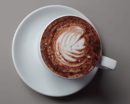 A cup of coffee decorated with a palm symbol and sprinkled with chocolate powder