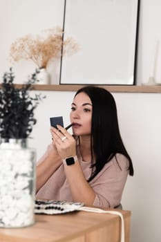 A brunette girl sitting at a desk in the office doing makeup