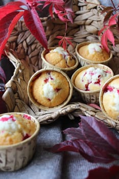 Fresh cupcakes in the basket are decorated with autumn leaves