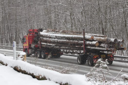 Birkenfeld, Germany February 6, 2018: A truck loaded with logs drives on a wintry road