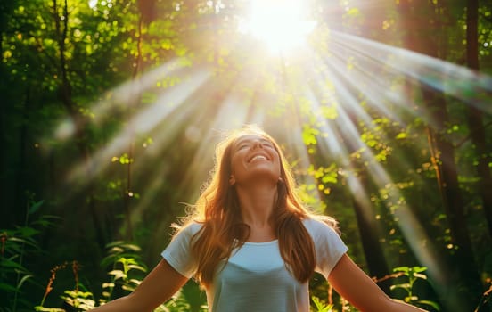 Happy woman with outstretched arms enjoy the sun in a green forest