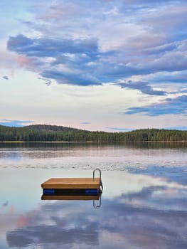 Swimming island in Sweden on a lake at sunset. Clouds reflected in the water. Swimming fun on vacation with recreation in Scandinavia