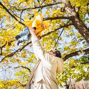 More, more,... dad, that's fun. Happy young father throws his cute little happy baby boy up in the air. Father's Day, Father and his son baby boy playing and hugging outdoors in nature in fall
