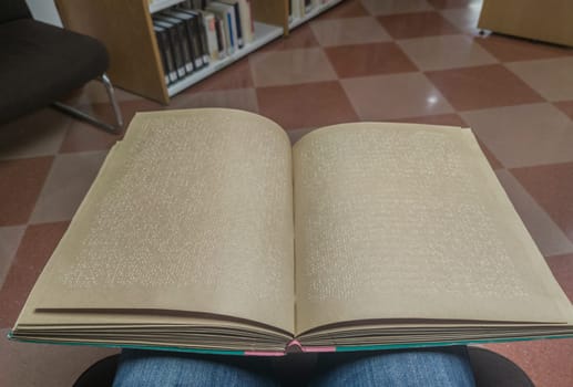 Blind male reading braille language book at library. Point of view shot