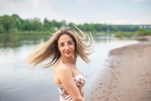 happy young woman with tousled hairs standing on riverbank