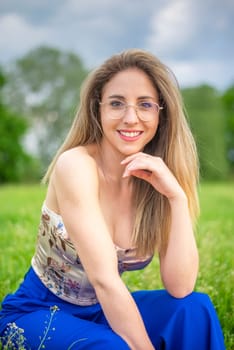 young woman with glasses sitting on a meadow