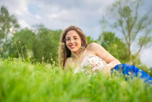 young woman with glasses lying on a meadow