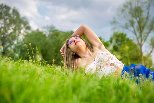 young woman with glasses lying on a meadow
