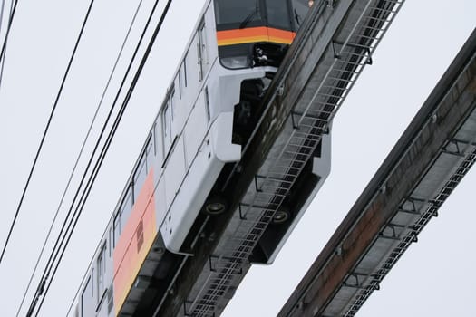 Monorail train in motion on elevated track with urban background, showcasing modern public transportation.