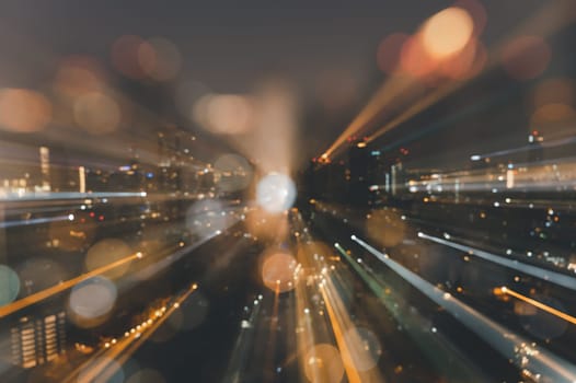 Blurred abstract background of skyscrapers at night with bokeh lights trail using zoom technique.