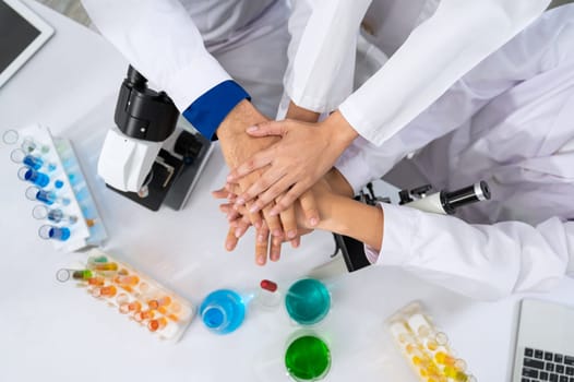 Scientists in white lab coat putting hands together in laboratory . Teamwork and successful concept