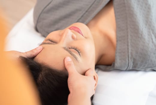 Relaxed and calm girl having spa facial massage in beauty salon. Traditional oriental massage therapy and beauty treatment. Spa skin and body care concept