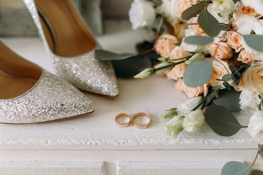 Wedding shiny shoes and wedding paraphernalia, gold wedding rings, wedding bouquet.View from above