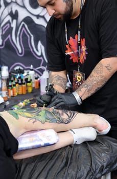 Krakow, Poland -  June 12, 2022: Unidentified  participant at 15th Tattoofest Convention in Cracow. One of the most prestigious tattoo festivals. Tattoo artist at work.