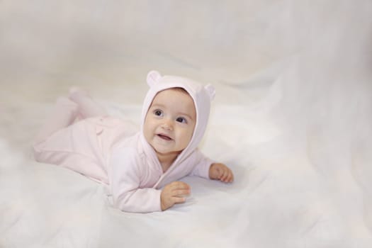Lying smiling child in a bear costume on a light background.View from above