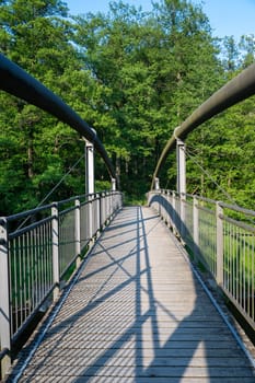 View of a metal and wooden pedestrian bridge in green nature