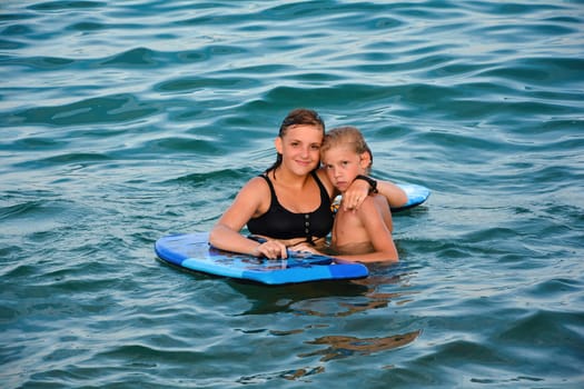 Two children with a swimming board in the water