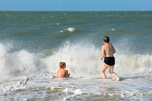 A boy and a teenage girl have fun in the waves on the sea beach,A boy and a teenage girl have fun in the waves on the sea beach