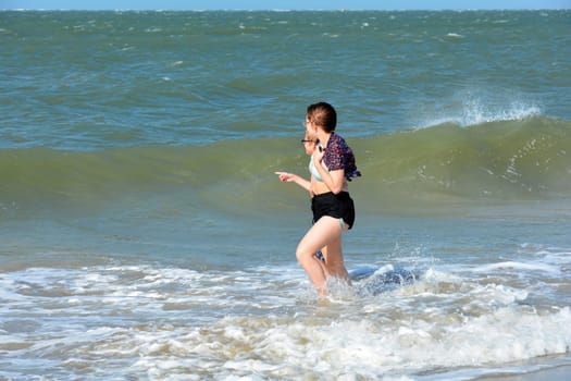 Two children run in the waves on the sea beach