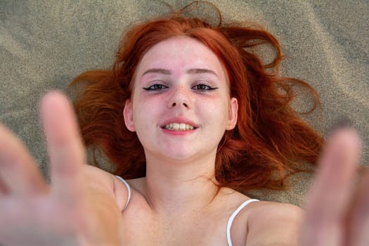 A young girl lies in the sand dunes in a white dress