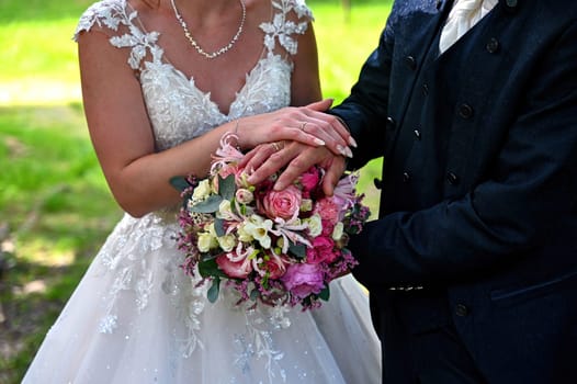 Bridal couple hands with golden rings and flower bouquet
