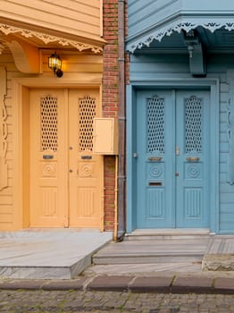 A pair of brightly colored doors, one in a deep turquoise blue and the other in a sunny lemon yellow, stand side-by-side on a narrow cobblestone street in Kuzguncuk neighborhood, Istanbul, Turkey