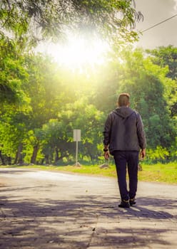Man walking in desolate street, man walking backwards walking in a street surrounded by trees