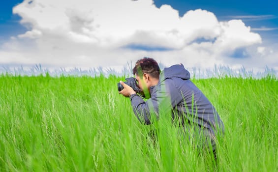 Man taking picture with camera in the field, photographer in the field taking a picture, Latino man in a green field taking a picture