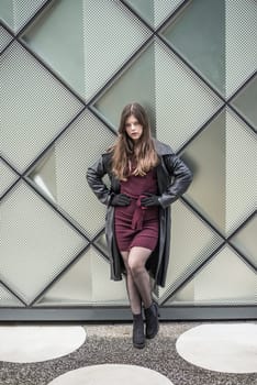 confident young woman with long black coat in the city