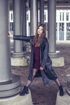 confident young woman with long black coat in the city