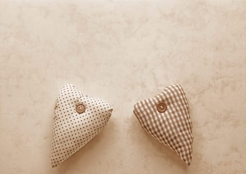Two fabric hearts in Peach Fuzz on a paper background